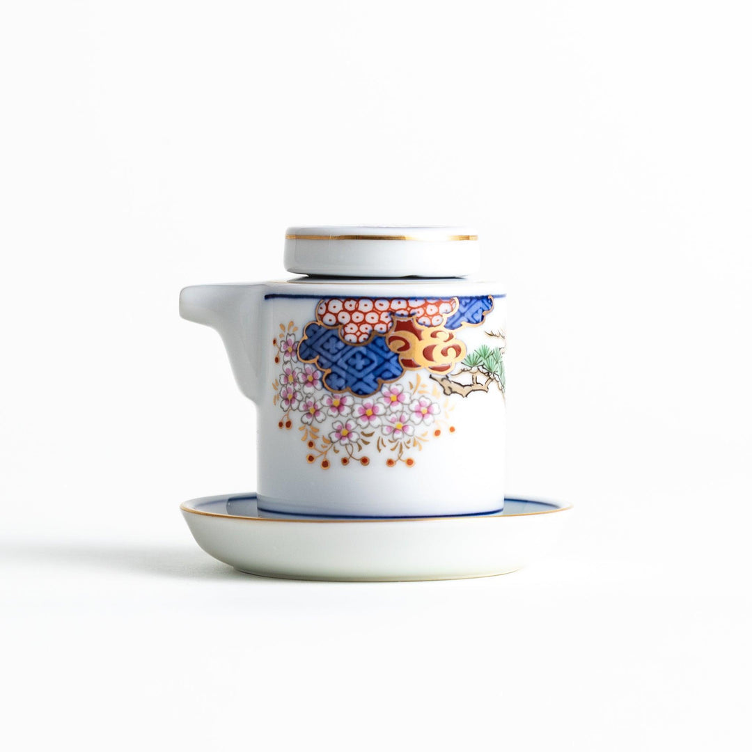 White Japanese sauce dispenser with blue red and gold patterns and matching saucer for elegant serving.