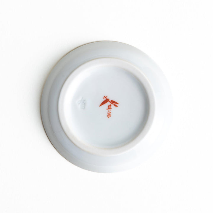 White Japanese sauce dispenser with blue red and gold patterns and matching saucer for elegant serving.