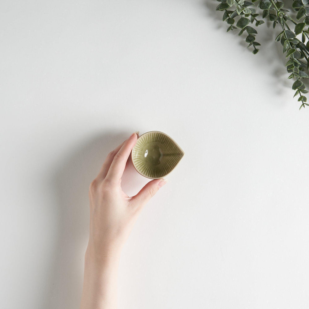 A small condiment bowl with a light green textured surface.