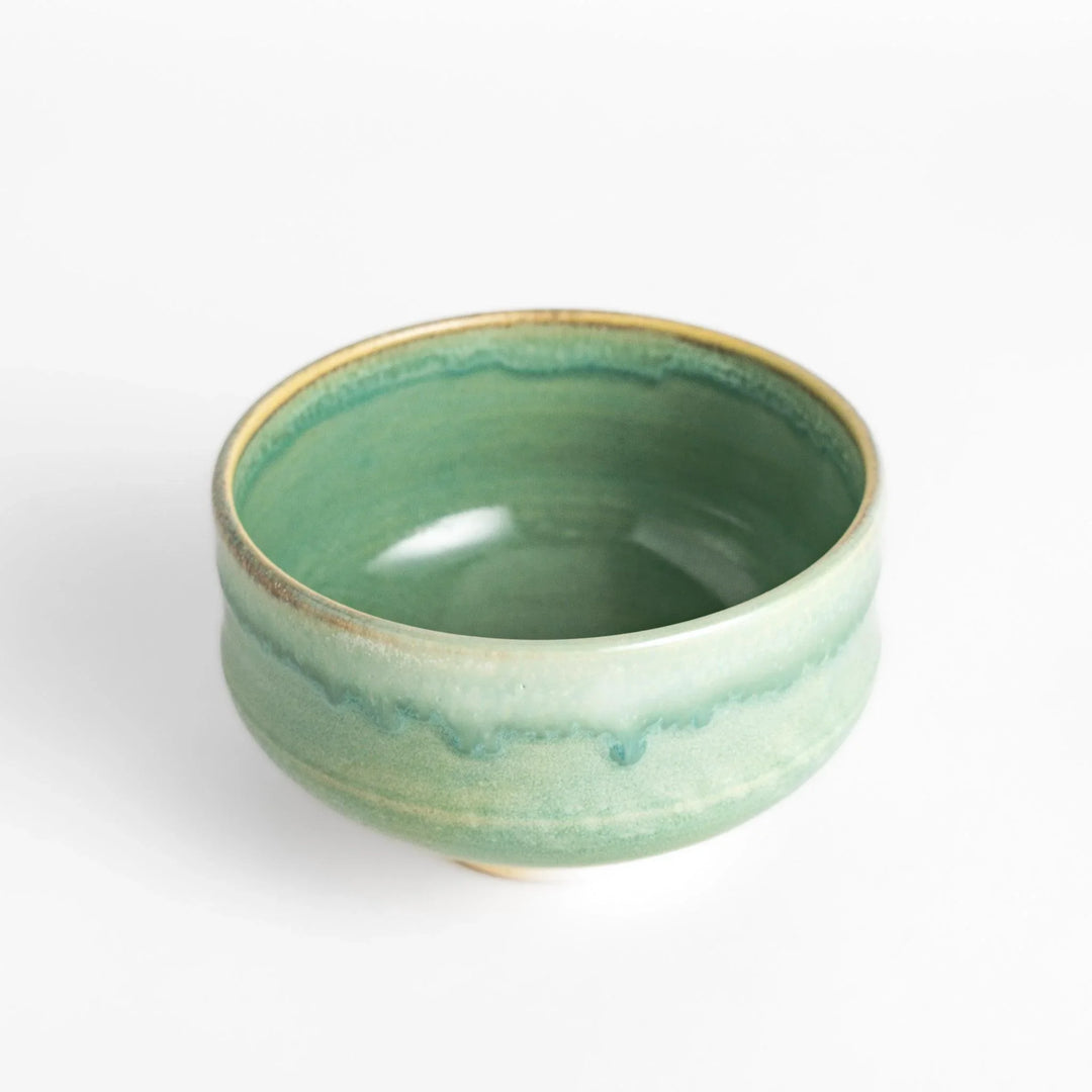 Green glazed ceramic matcha bowl with a rustic base, perfect for preparing and savoring matcha in a traditional tea ceremony.