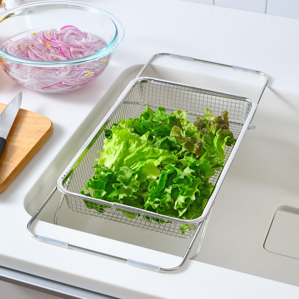 Fine mesh stainless steel draining basket, ideal for washing or draining ingredients during food preparation.