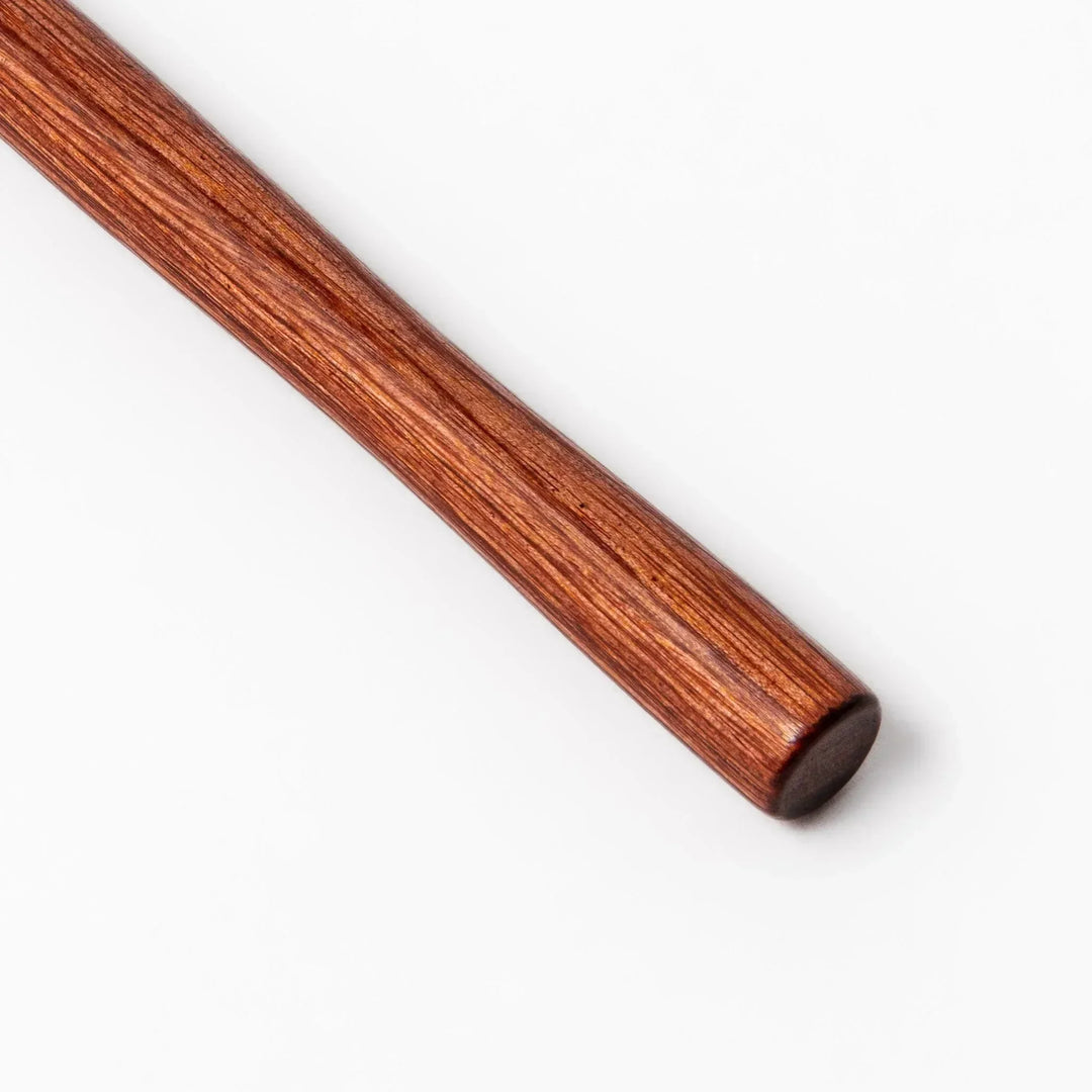 Stainless steel round-mesh skimmer with long wooden handle, perfect for straining soups and frying in home kitchens.