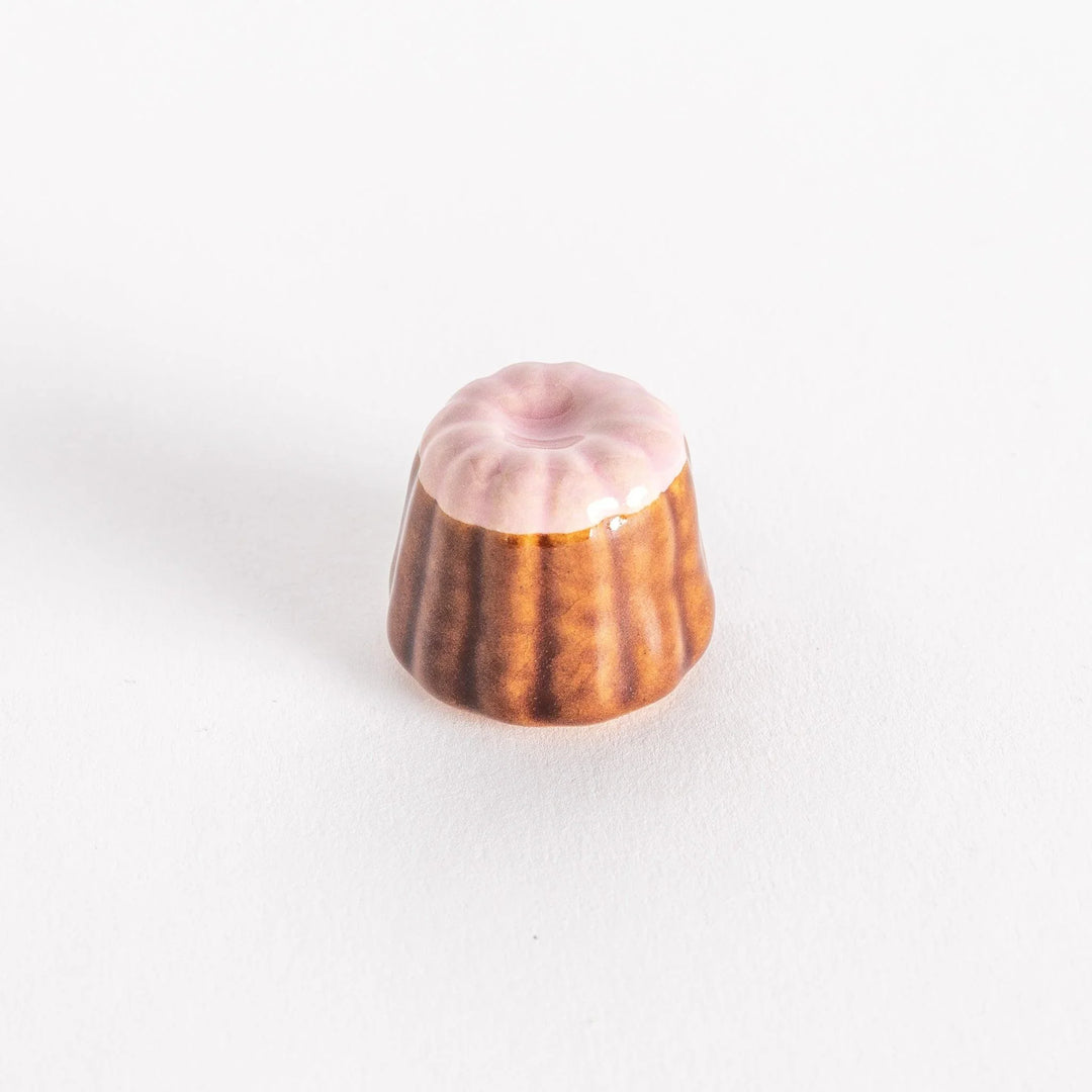 Strawberry canelé shaped ceramic chopstick rest with pink top and brown ridged base for cute look.