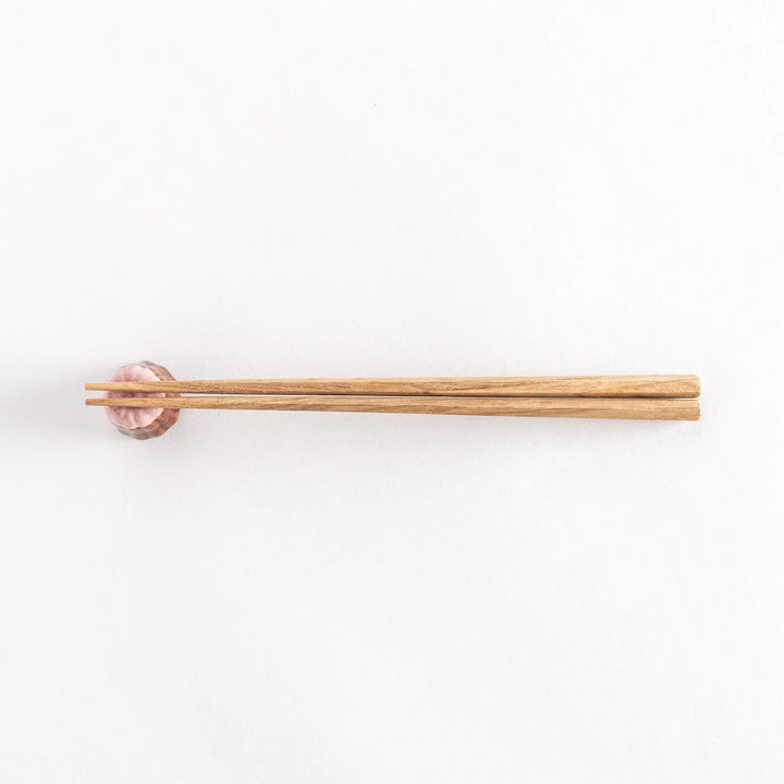 Strawberry canelé shaped ceramic chopstick rest with pink top and brown ridged base for cute look.