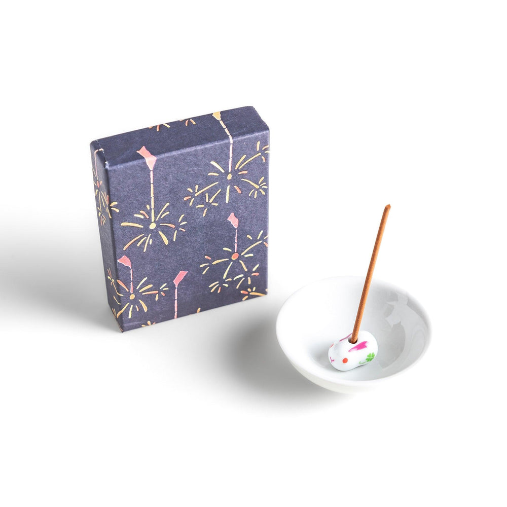Japanese incense with brown sticks in dark blue box decorated with fireworks for soothing summer aroma.