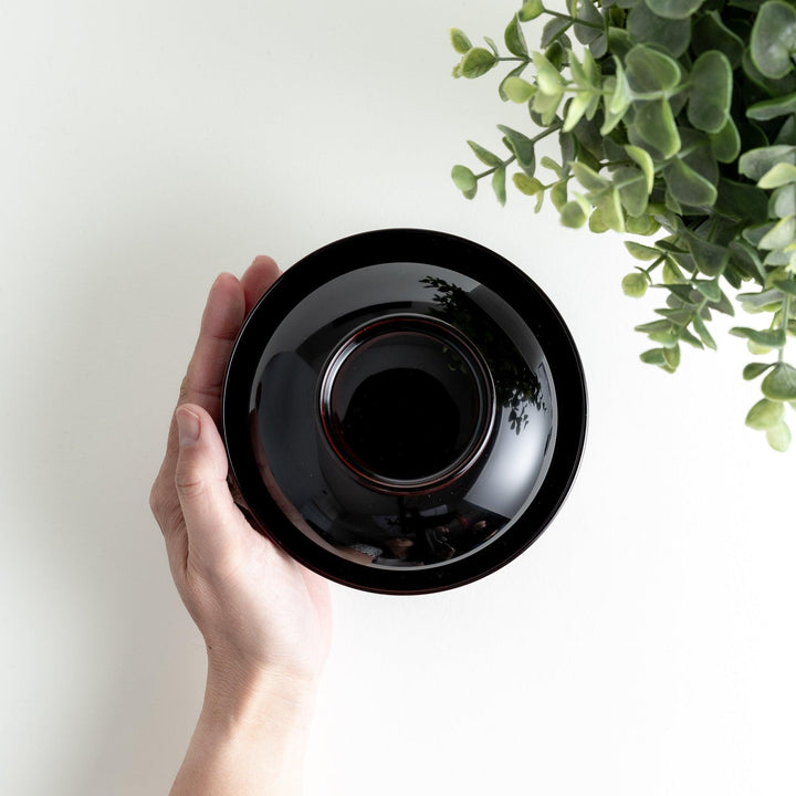 Traditional black lacquer bowl with red interior, featuring a gold pine tree design on the lid.