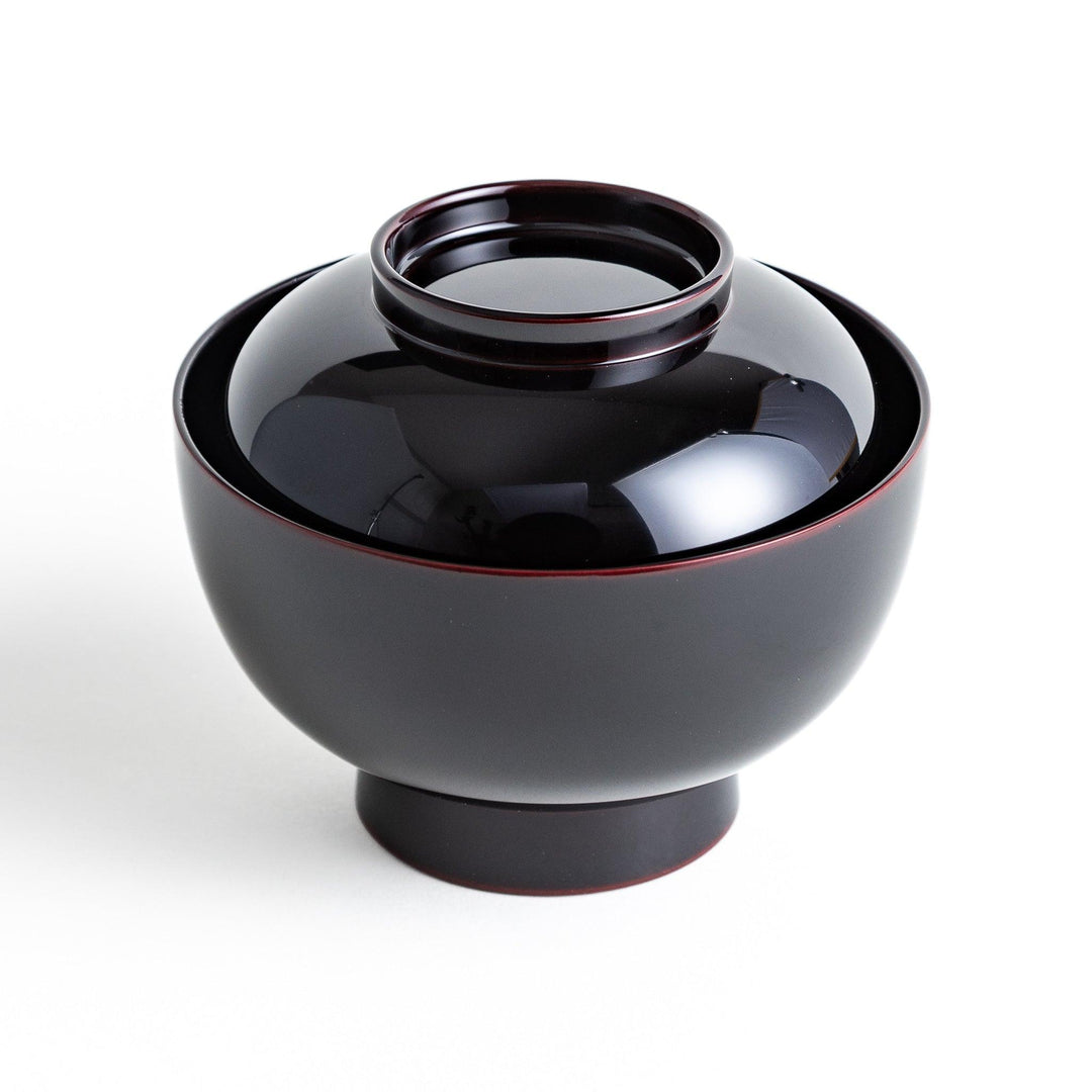 Traditional black lacquer bowl with red interior, featuring a gold pine tree design on the lid.