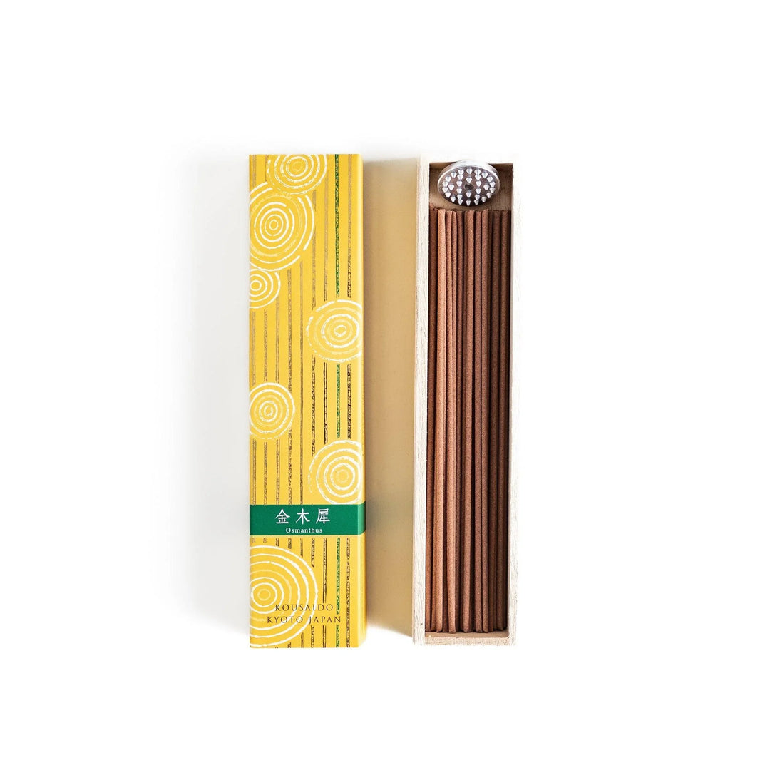 Japanese incense in wooden box with brown sticks and yellow design featuring white circle patterns.