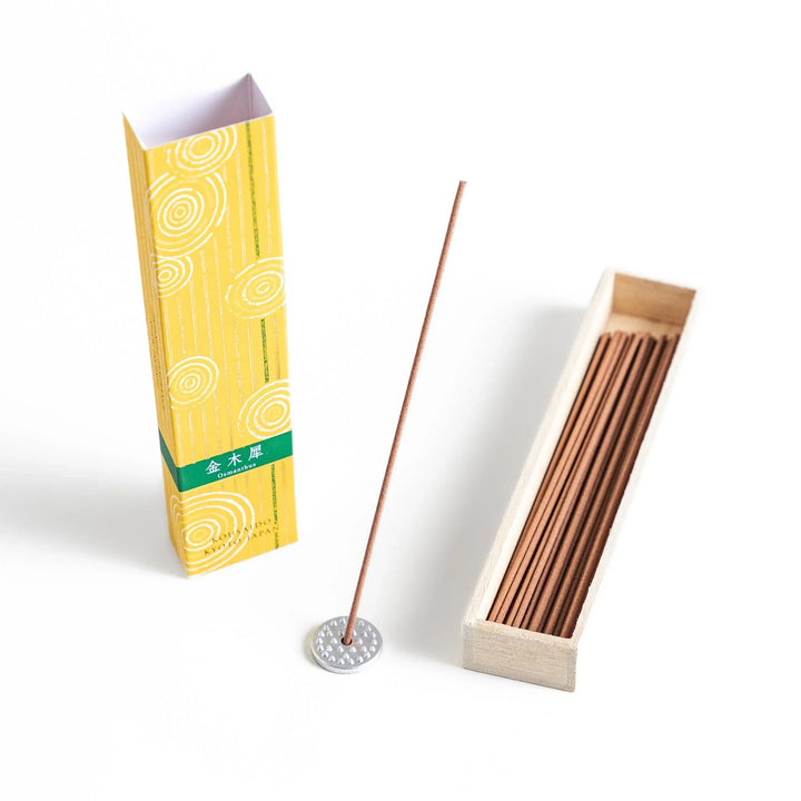Japanese incense in wooden box with brown sticks and yellow design featuring white circle patterns.