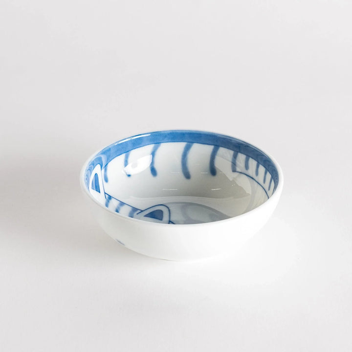 A dessert bowl with a blue-striped cat, smiling contentedly.