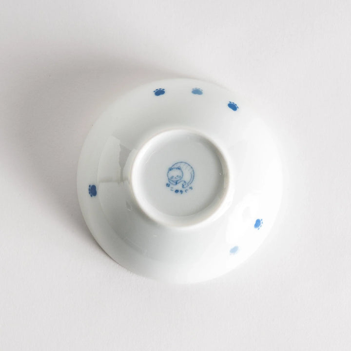 A dessert bowl with a blue-striped cat, smiling contentedly.