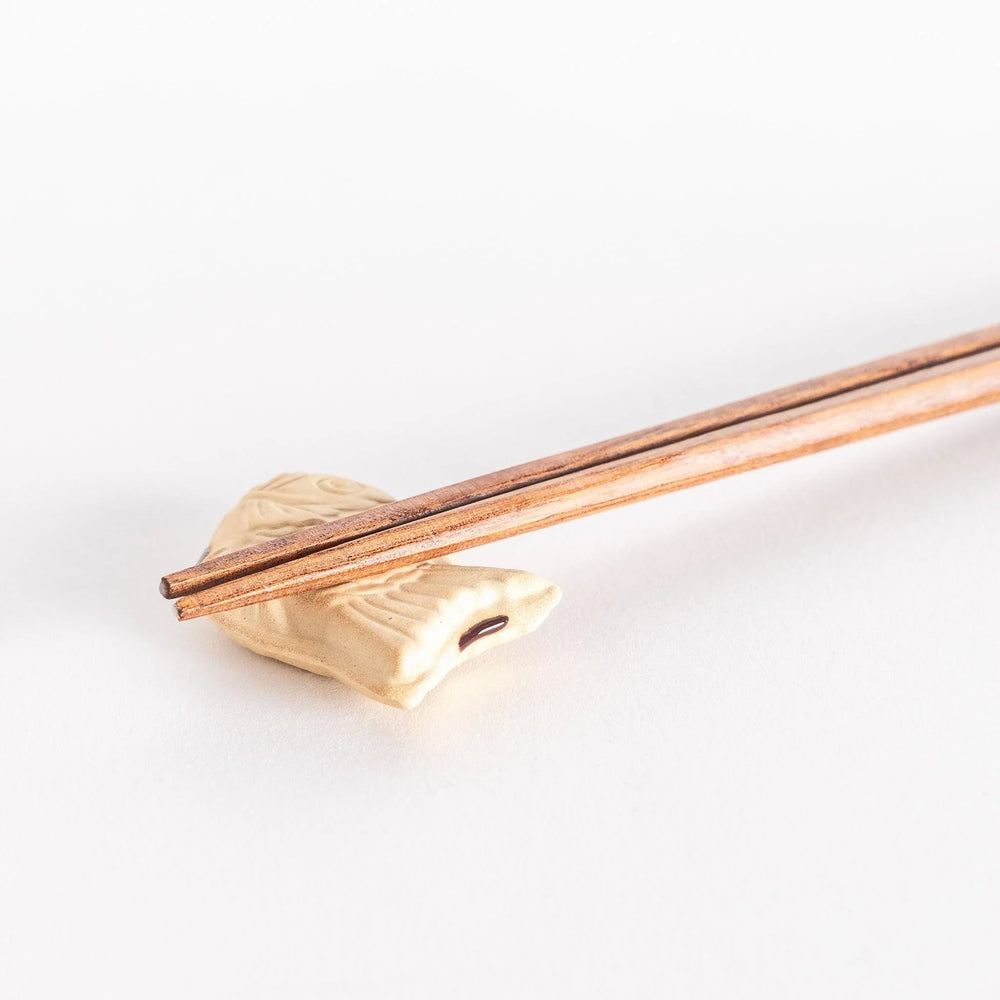 Close-up view of the taiyaki chopsticks rest with chopsticks resting on top, showcasing its textured fish design.