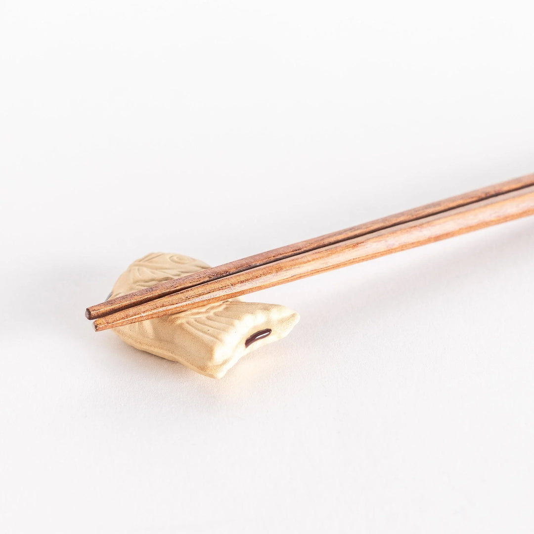 Close-up view of the taiyaki chopsticks rest with chopsticks resting on top, showcasing its textured fish design.