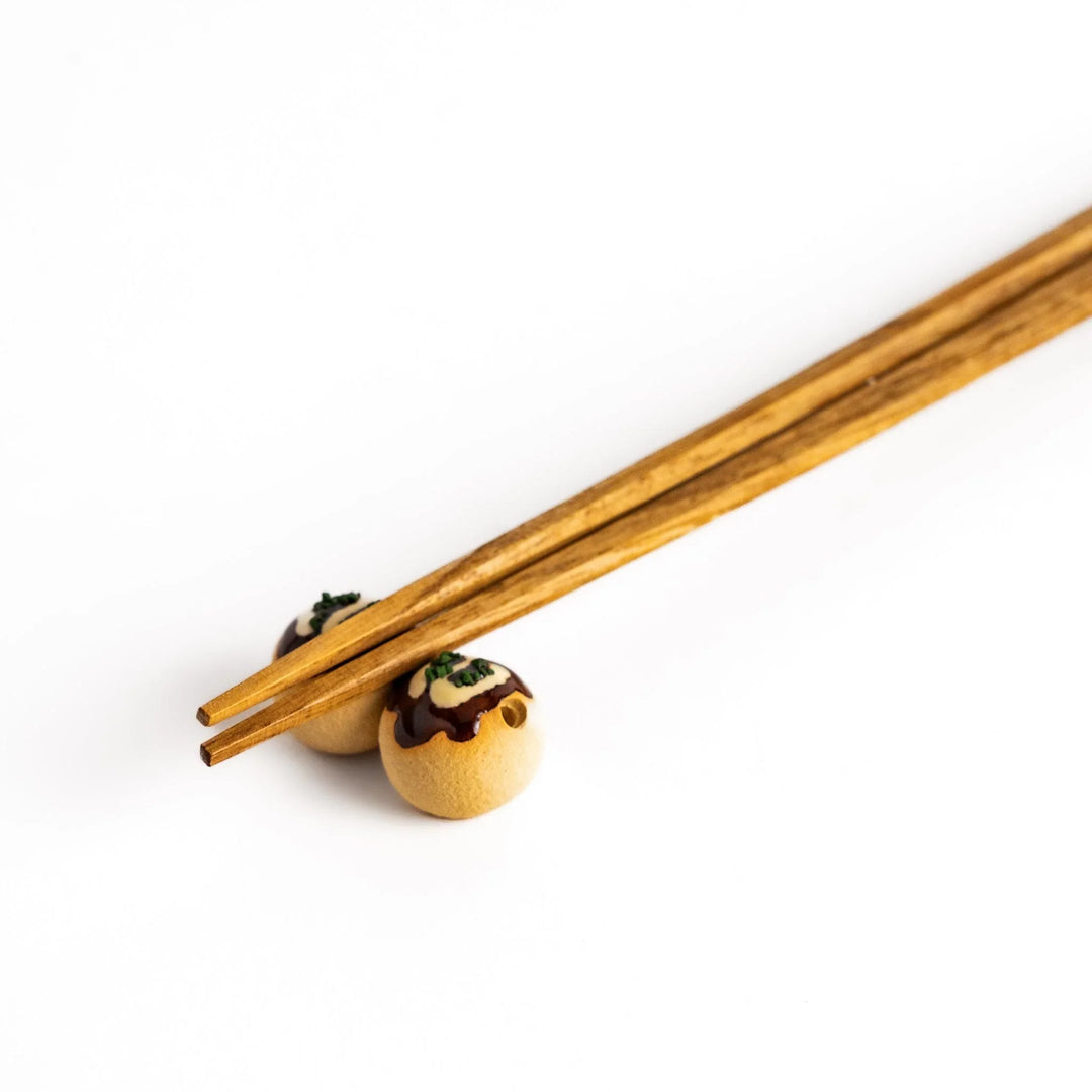 Takoyaki ball shaped ceramic chopstick rest with sauce and topping details for playful Japanese dining.