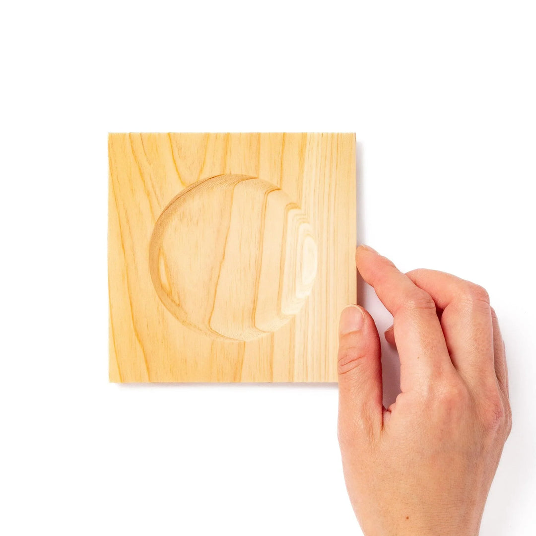 Square hinoki wood coaster with recessed circular center and beveled edge, featuring natural grain for elegant cup support.
