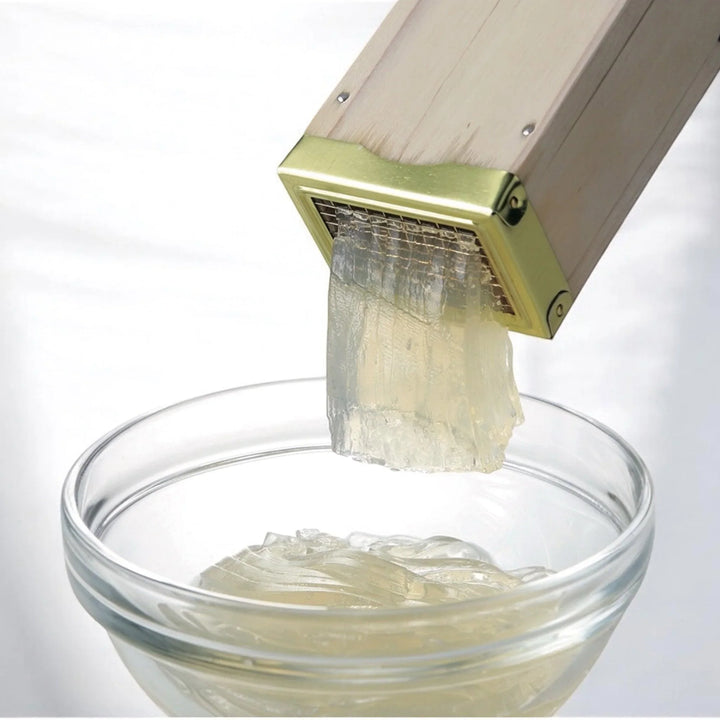 Tokoroten press with brass blade for shaping Japanese jelly noodles into delicate strands for dessert.