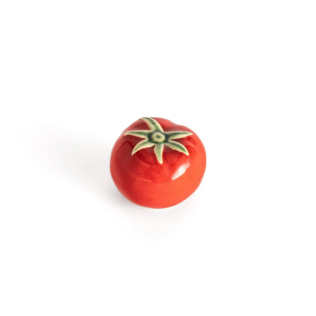 Glossy red ceramic tomato chopstick rest with green stem bringing playful yet elegant touch to tableware.