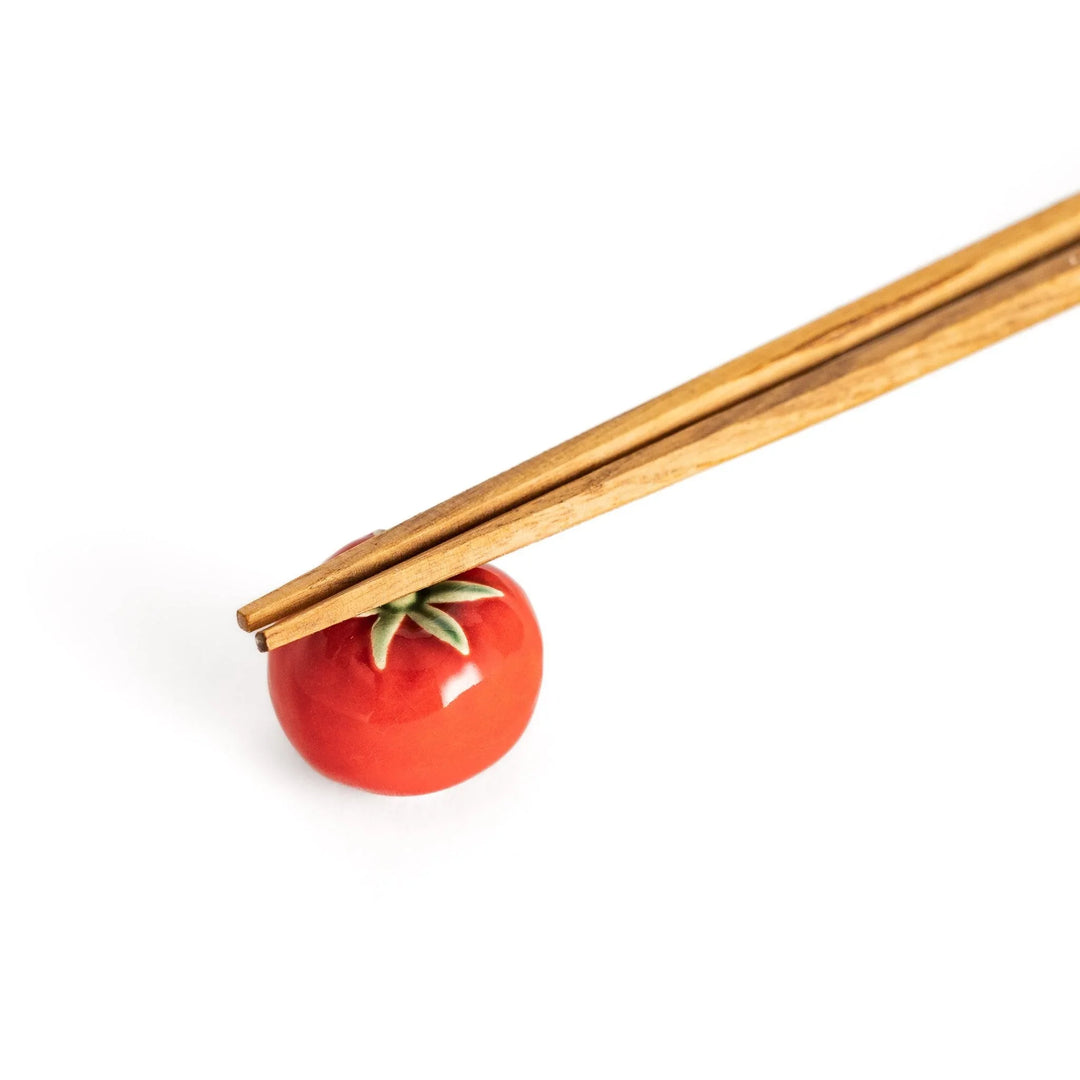Wooden chopsticks balanced on the glossy red tomato chopstick rest, showcasing its functional and decorative design.