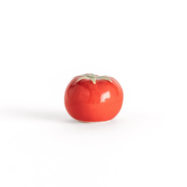 Glossy red ceramic tomato chopstick rest with green stem bringing playful yet elegant touch to tableware.