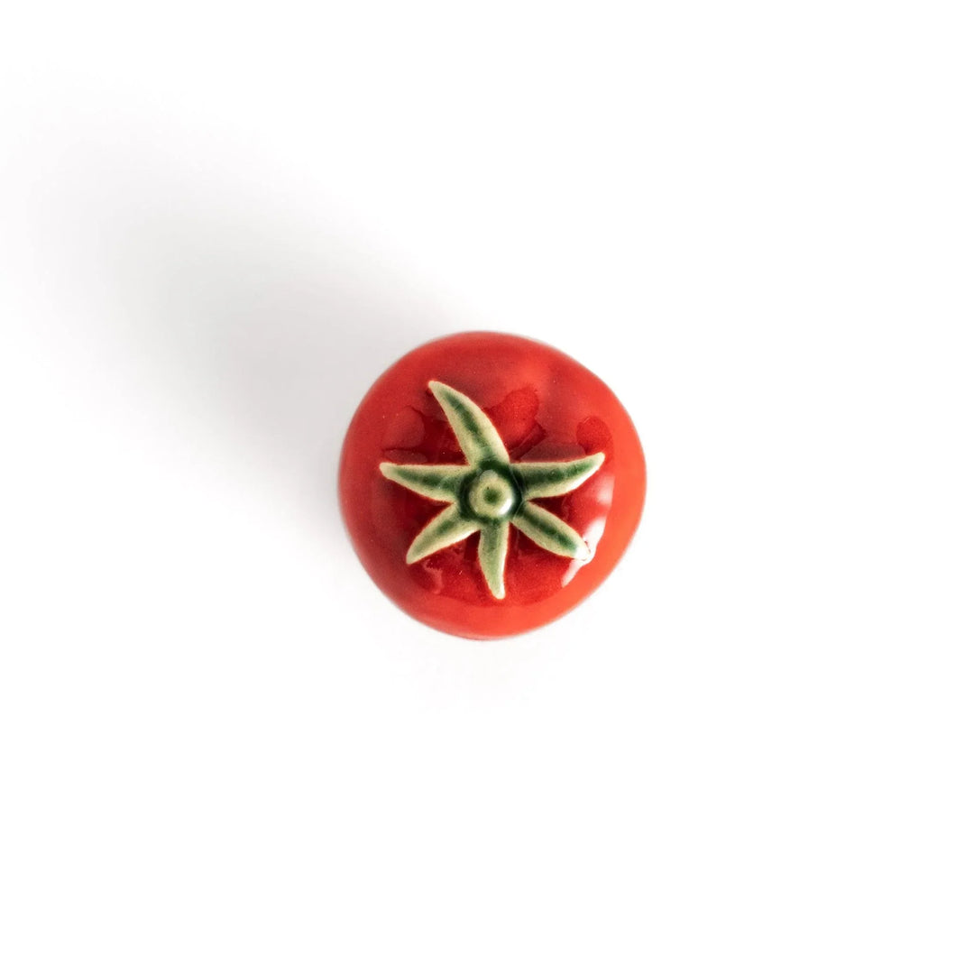 Glossy red ceramic tomato chopstick rest with green stem bringing playful yet elegant touch to tableware.