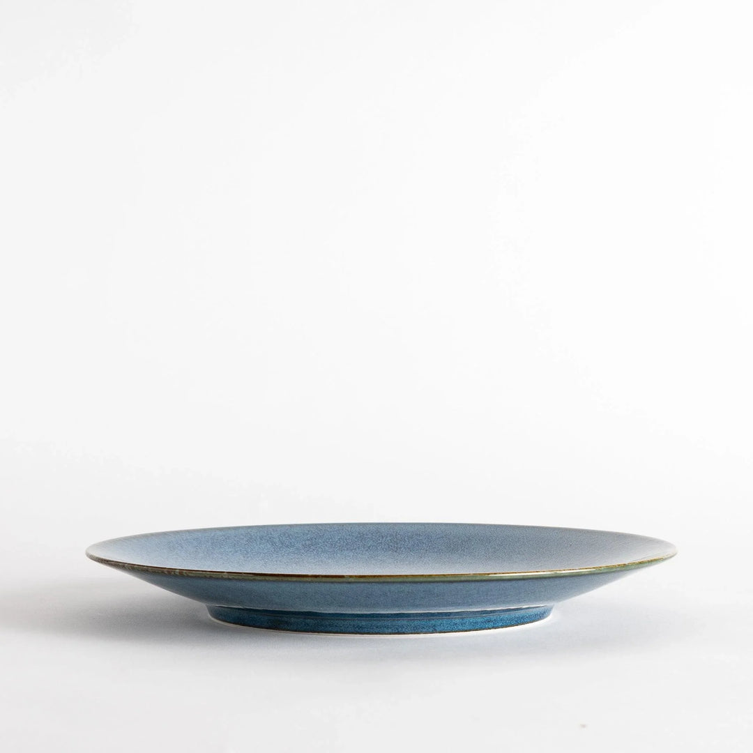 A round dinner plate with a deep blue gradient finish and a subtle textured surface.