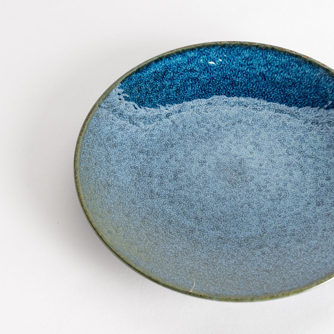 A round salad plate featuring a deep blue color and a fine speckled texture.