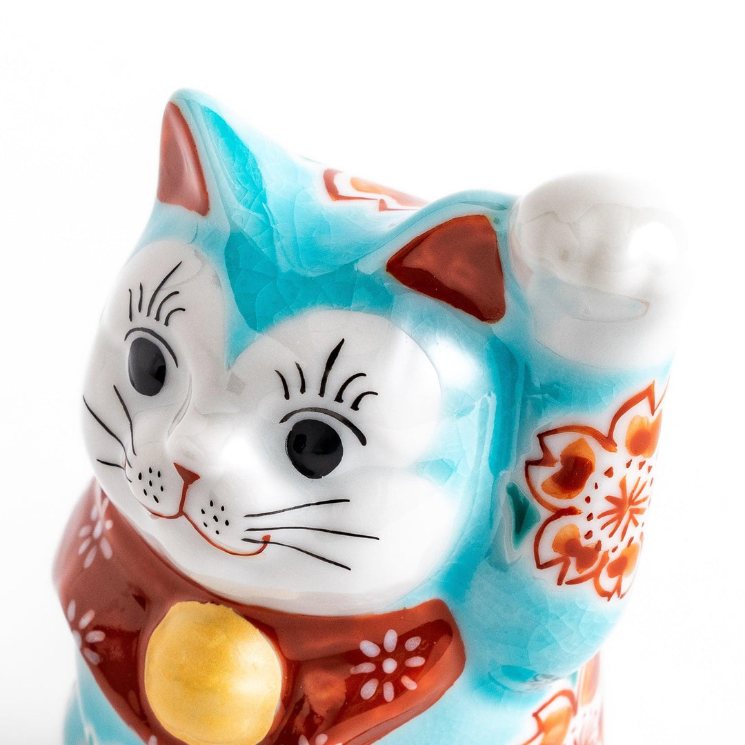 Turkish blue Japanese Maneki Neko figurine with floral patterns golden bell and raised paw for good fortune.