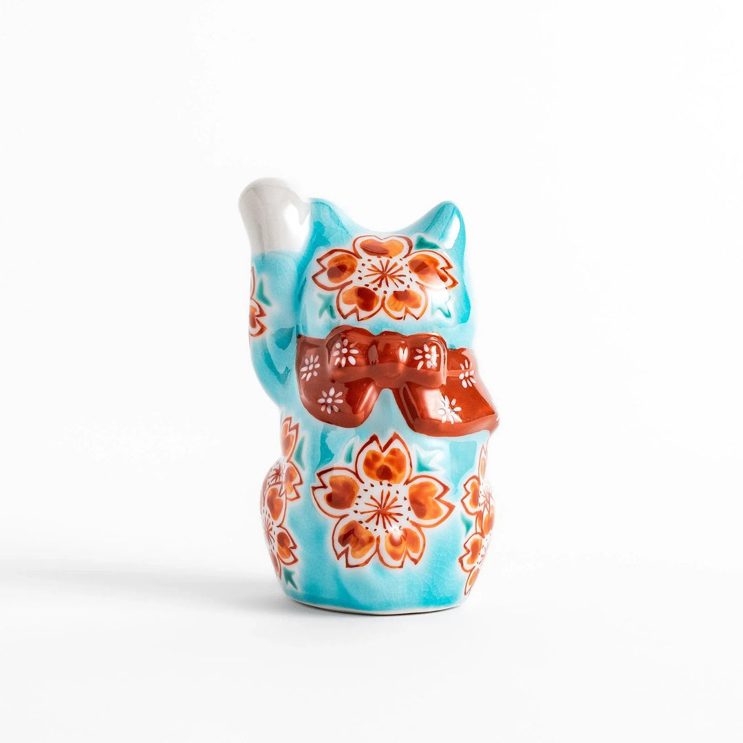 Turkish blue Japanese Maneki Neko figurine with floral patterns golden bell and raised paw for good fortune.