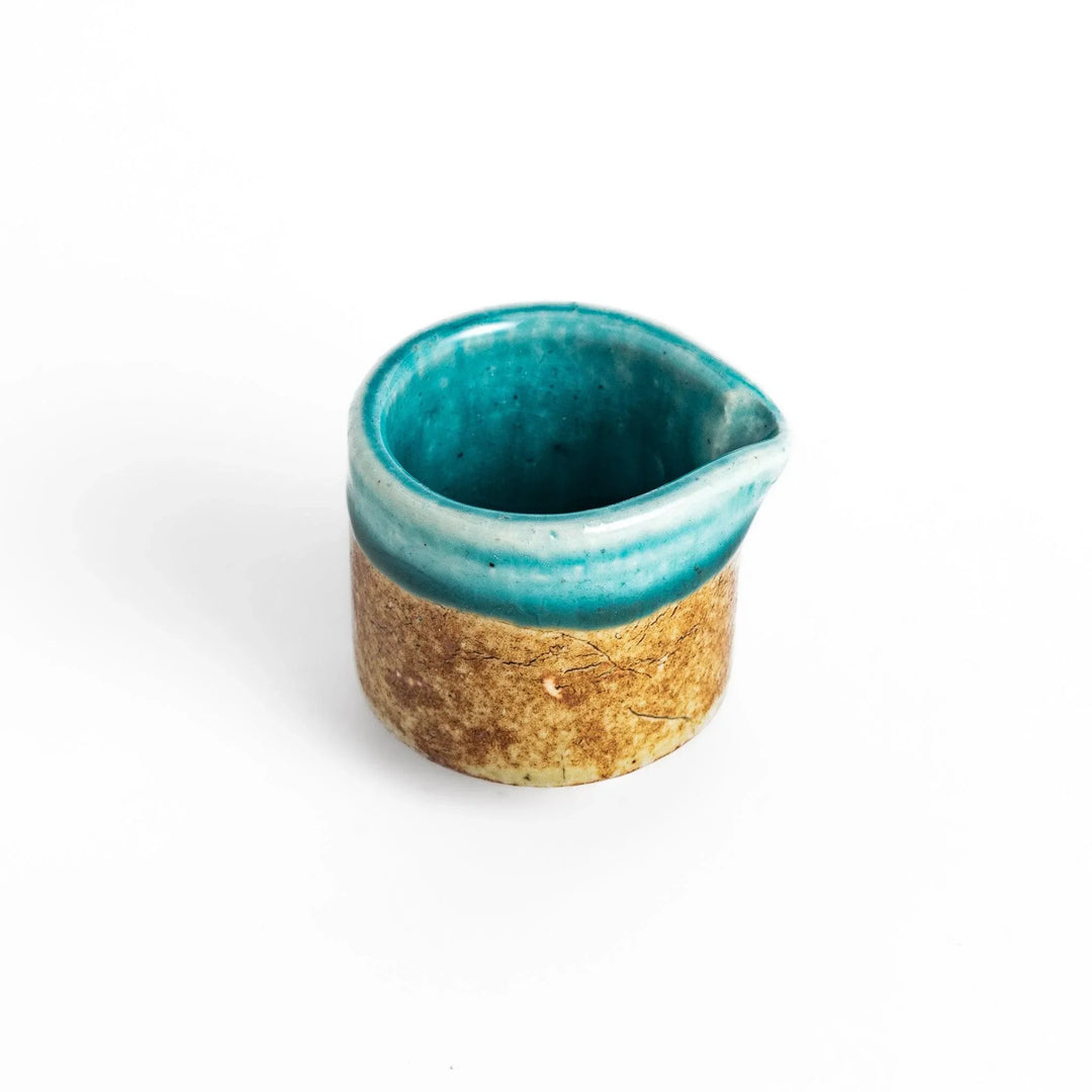 Turquoise sauce pourer with a smooth glaze and textured base, perfect for serving sauces or dressings.