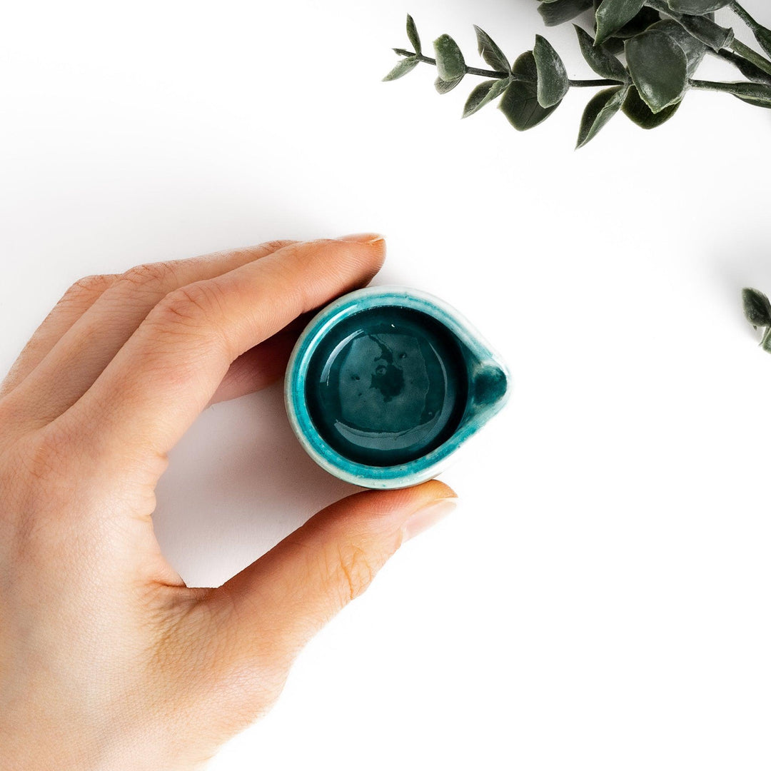 Turquoise sauce pourer with a smooth glaze and textured base, perfect for serving sauces or dressings.