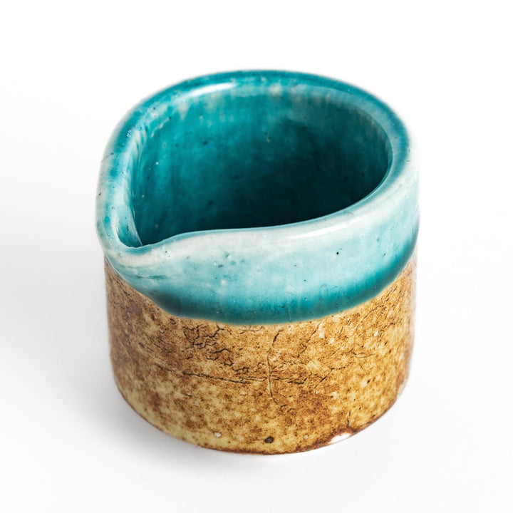 Turquoise sauce pourer with a smooth glaze and textured base, perfect for serving sauces or dressings.