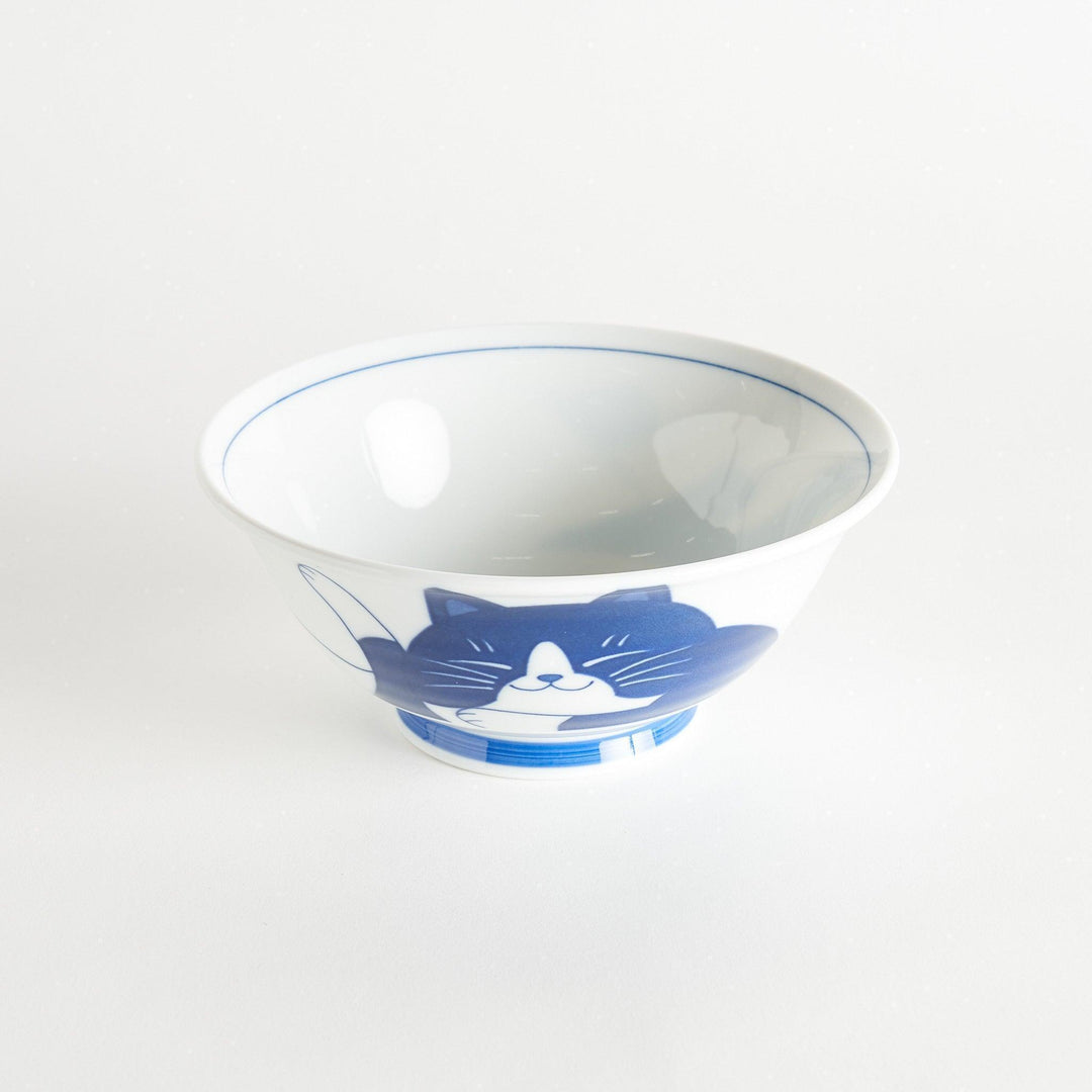 A white ramen bowl featuring a playful blue cat lying down with its eyes closed.