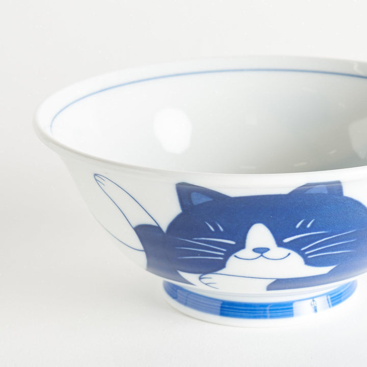 A white ramen bowl featuring a playful blue cat lying down with its eyes closed.