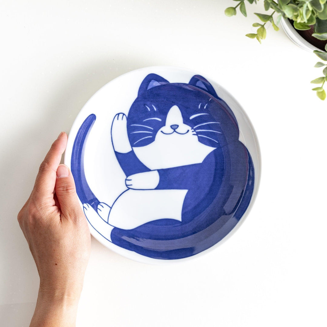 A salad plate featuring a playful black and white cat stretching contentedly.