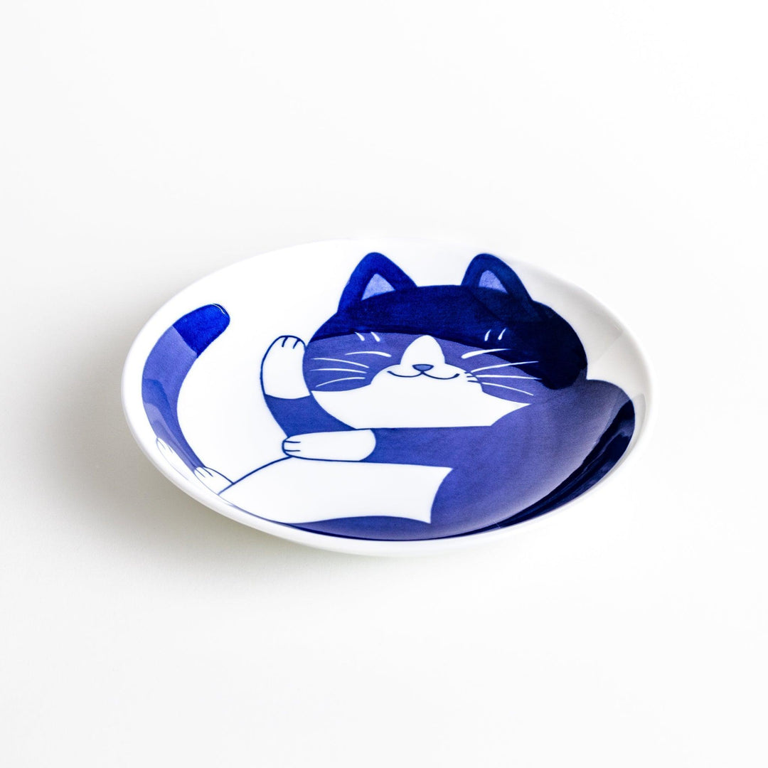 A salad plate featuring a playful black and white cat stretching contentedly.