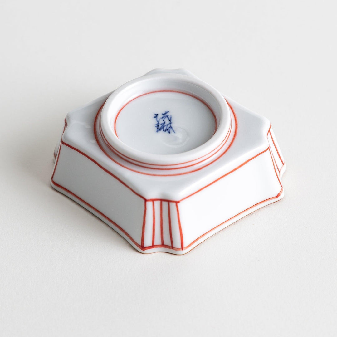 A small square dish with red and blue vertical stripes along the edges, accompanied by a silver spoon.