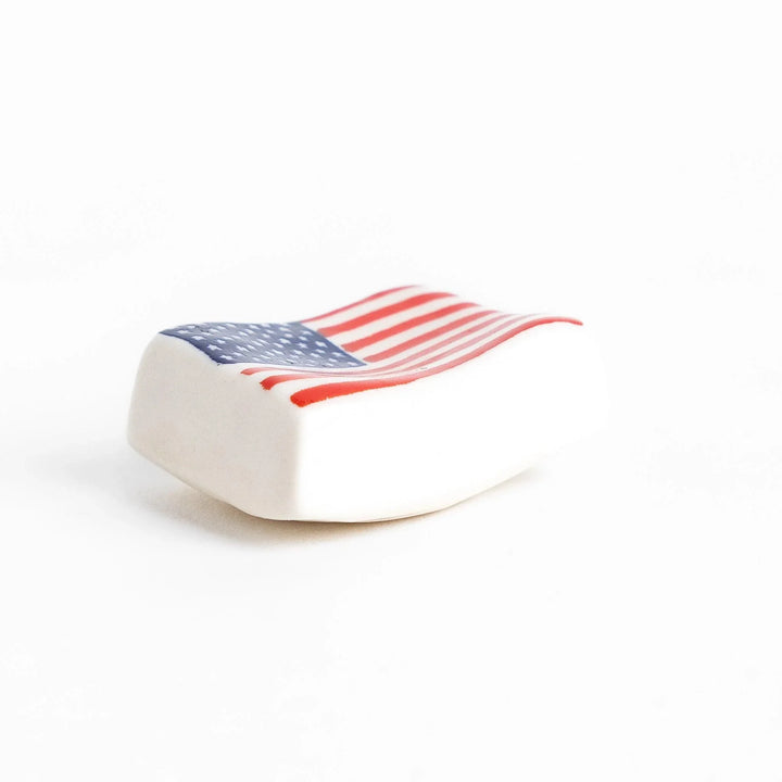 Chopstick rest shaped like the United States flag, featuring red and white stripes with a blue field of white stars.