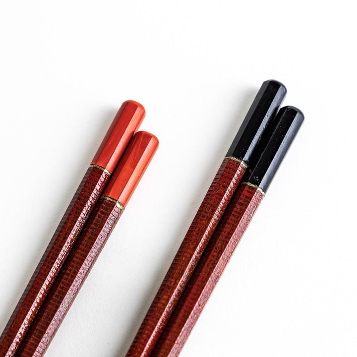 Chopsticks with red and black handles, featuring a rustic and traditional Japanese design.