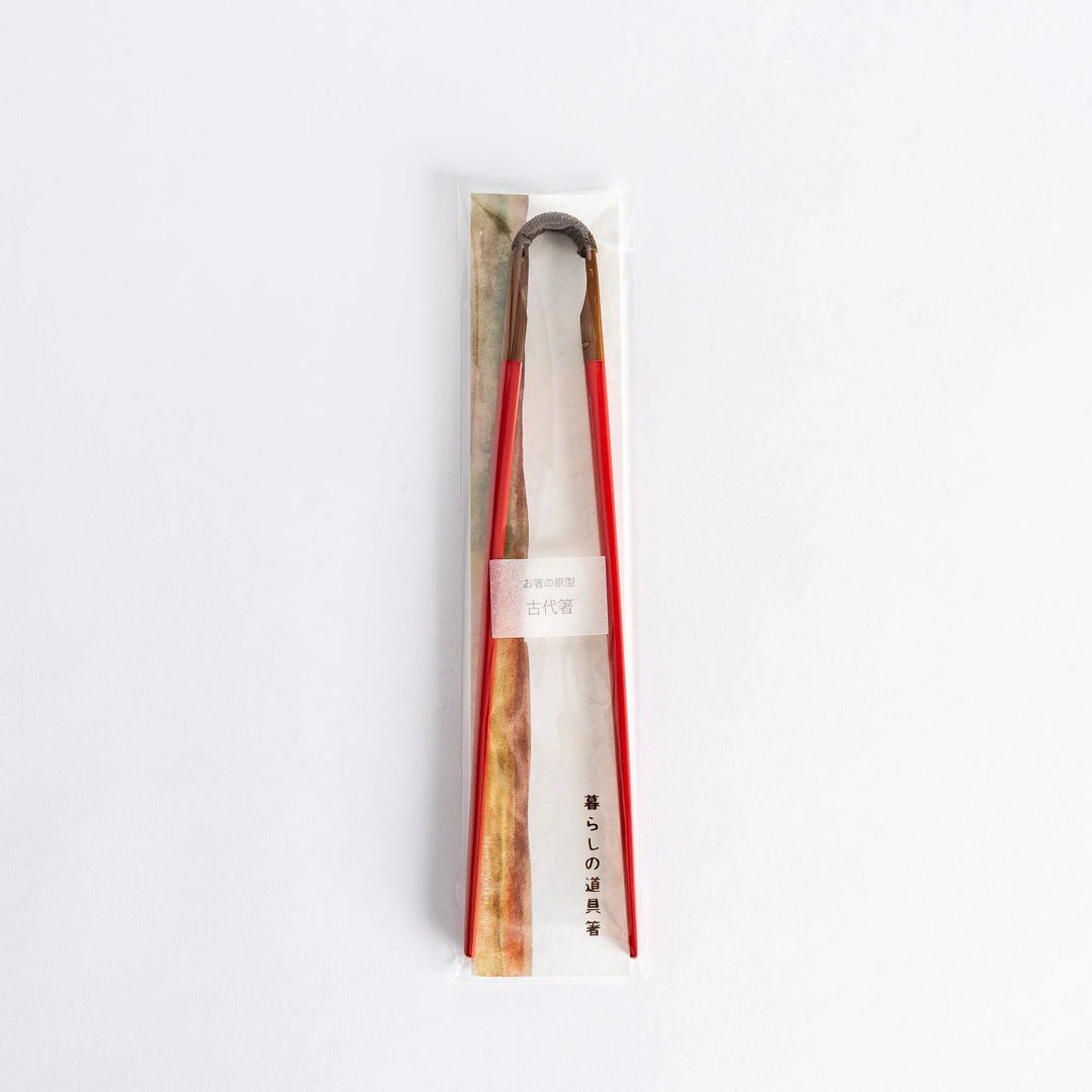 Red chopsticks with curved wooden joint showing natural wood connection and elegant Japanese craftsmanship.