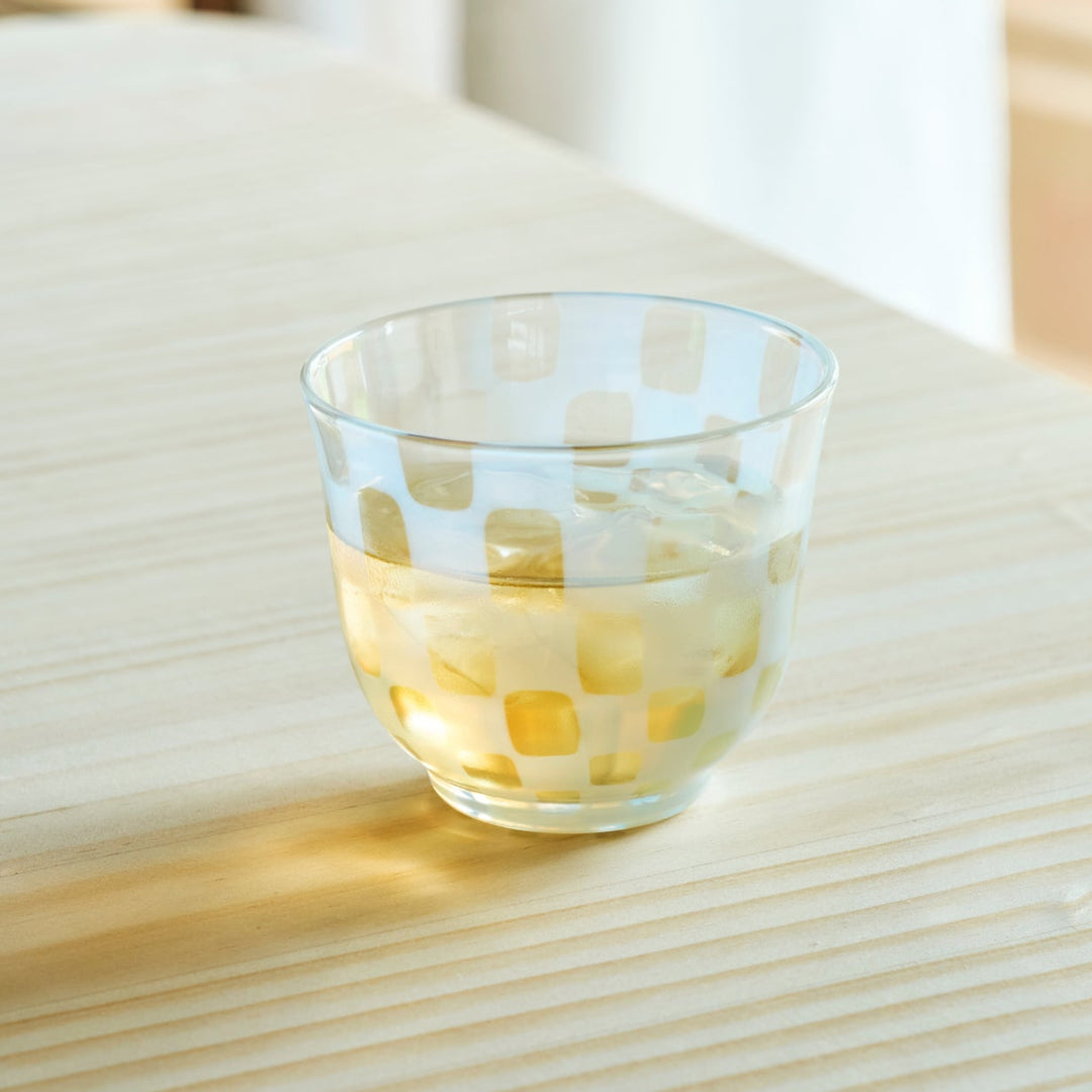 Vintage checkered glass cup filled with iced tea on a wooden table for a refreshing and stylish Japanese tea time