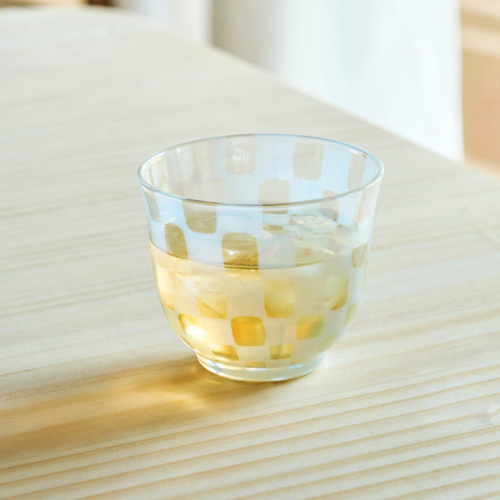 Vintage checkered glass cup filled with iced tea on a wooden table for a refreshing and stylish Japanese tea time