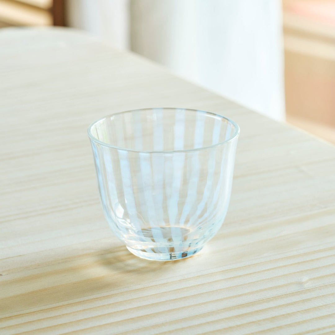 Vintage striped glass tea cup with vertical ridges clear Japanese style tumbler on wooden table minimalist tableware