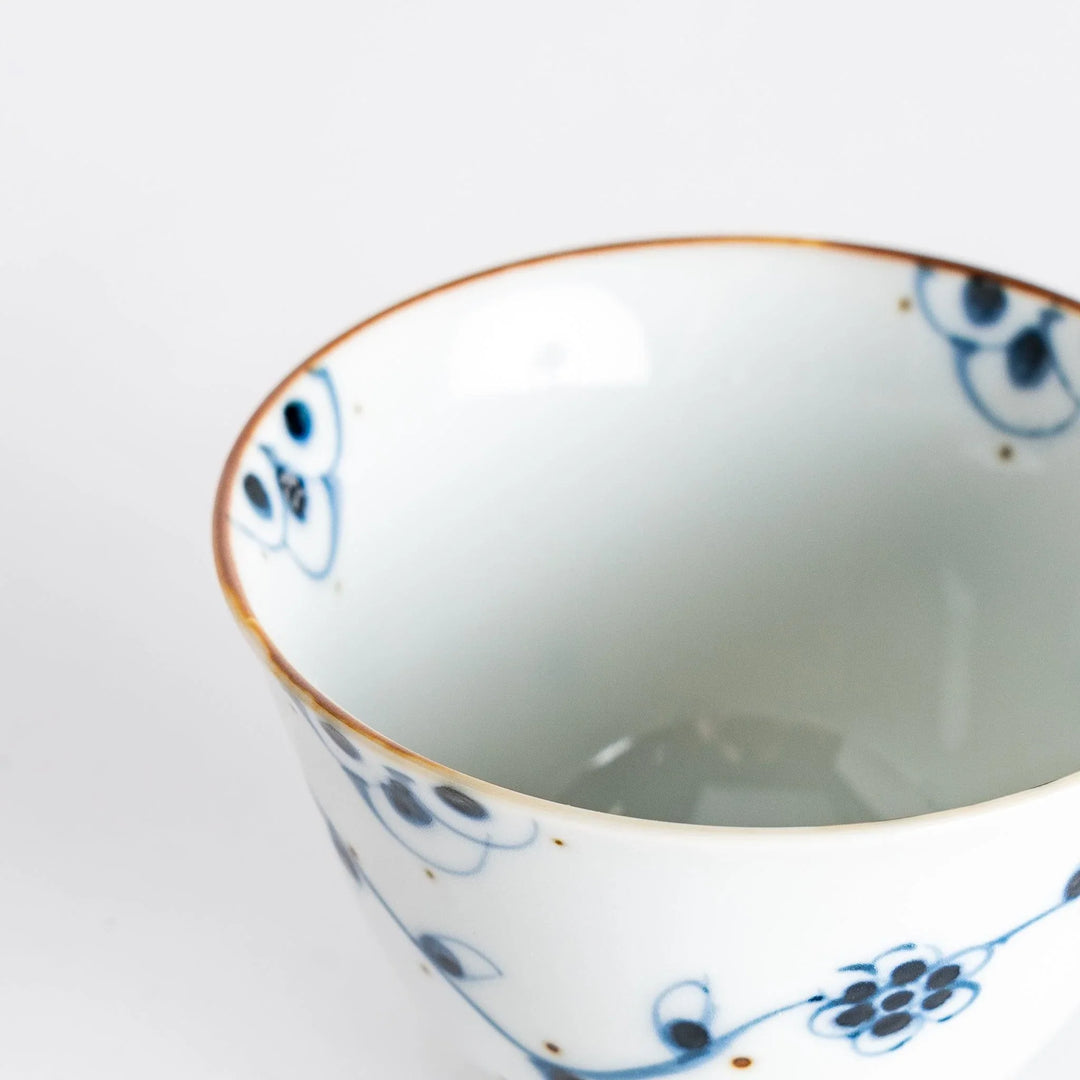 Close-up view of the teacup's rim, highlighting the fine details of the floral design and craftsmanship.