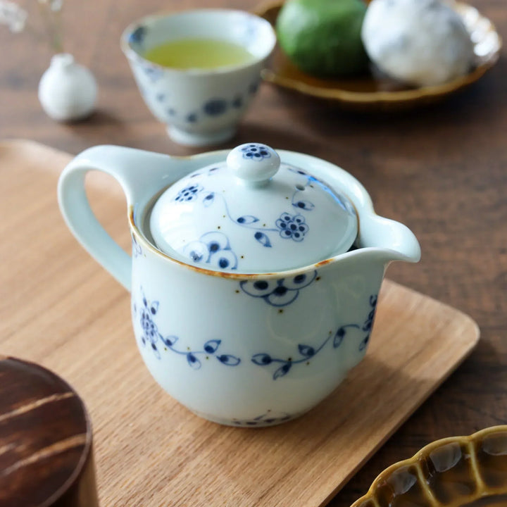 Hand painted white porcelain teapot with two matching cups featuring blue vine motifs on ash wood tray.
