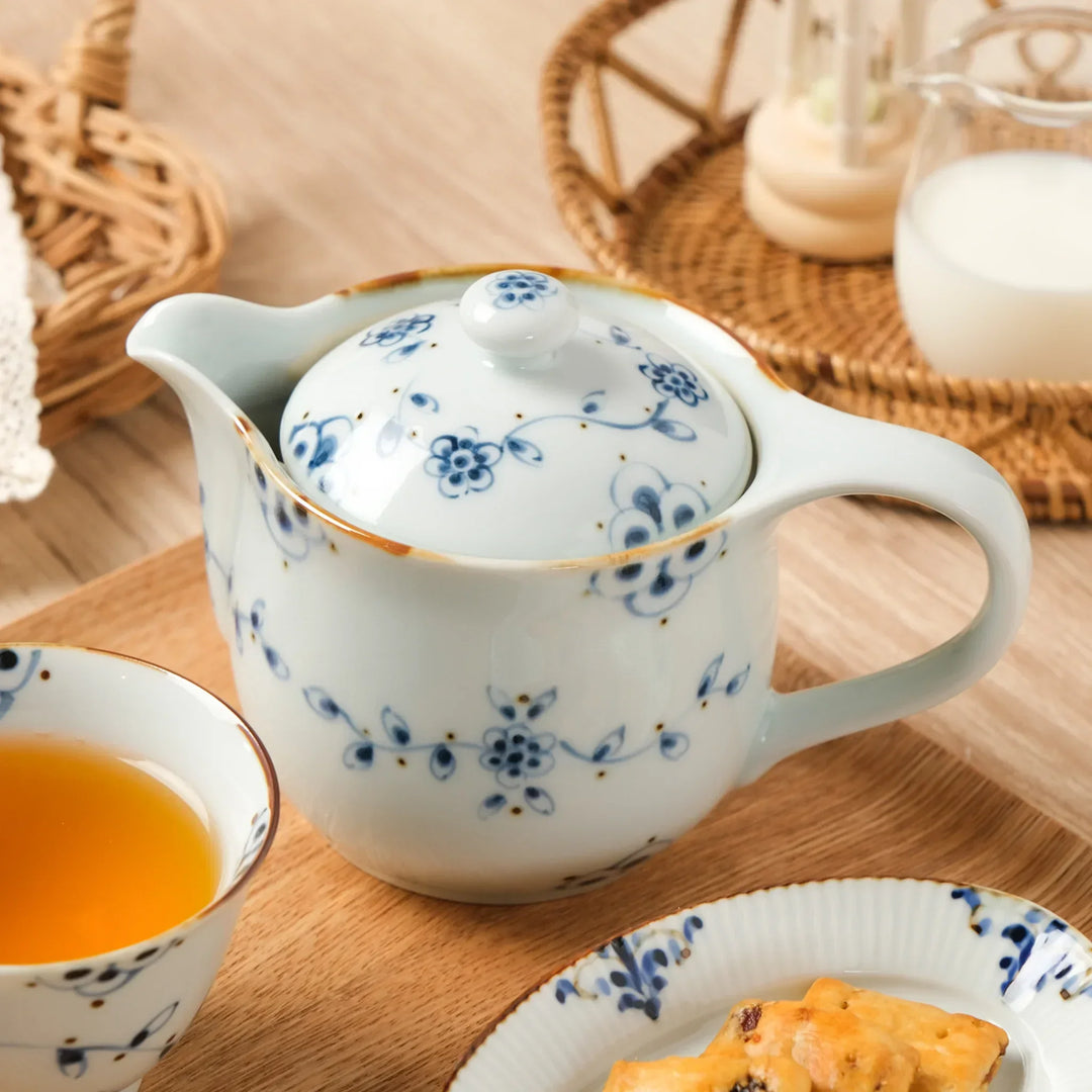 Vintage Japanese teapot with blue vine flower patterns, served with tea on a wooden tray.