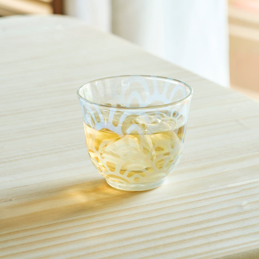 Vintage wave glass cup filled with iced tea on a wooden table for a refreshing and authentic Japanese tea time