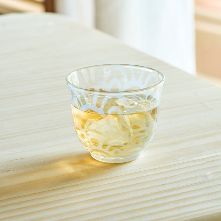 Vintage wave glass cup filled with iced tea on a wooden table for a refreshing and authentic Japanese tea time