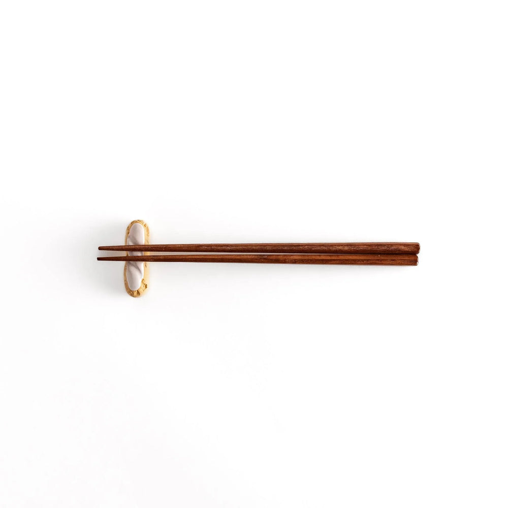 White chocolate éclair chopstick rest with golden brown base and glossy white top for elegant realistic design.