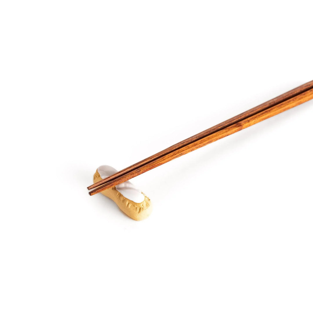 White chocolate éclair chopstick rest with golden brown base and glossy white top for elegant realistic design.