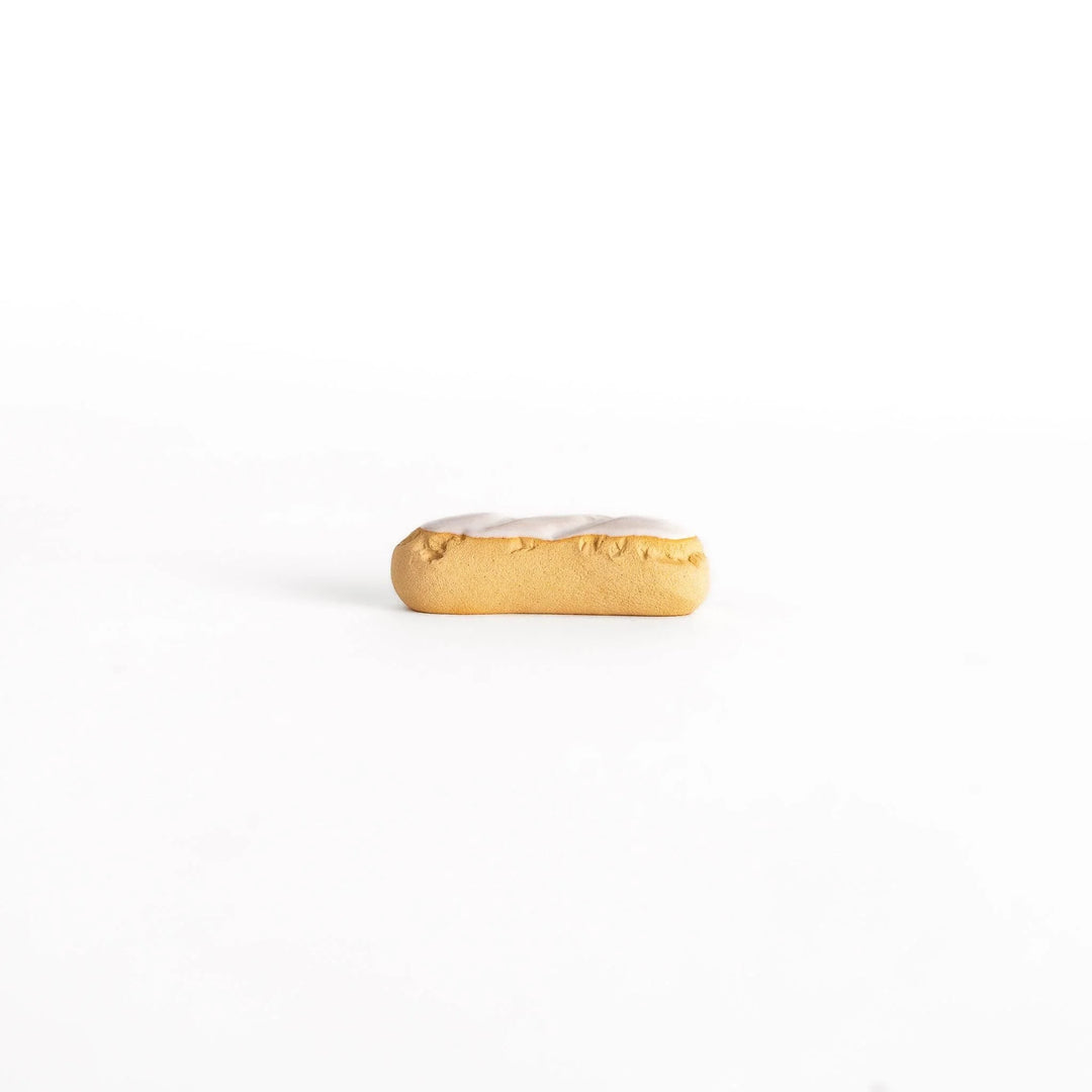 White chocolate éclair chopstick rest with golden brown base and glossy white top for elegant realistic design.